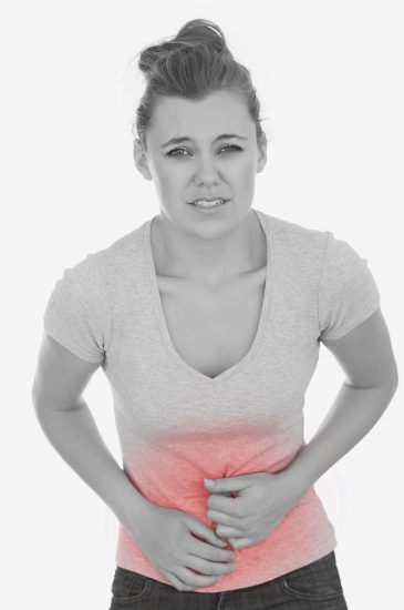 Portrait of unhappy young woman suffering from stomach pain against white background